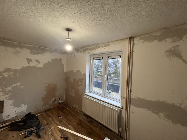 Living room walls in Southampton with plaster repairs around windows and radiator before painting.