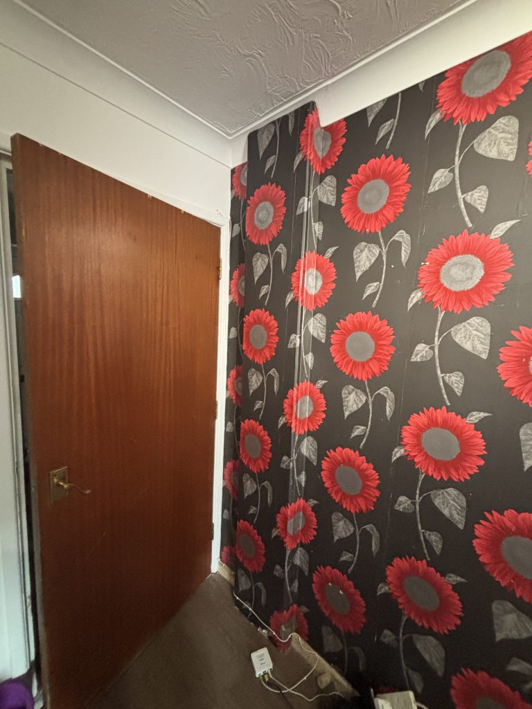 Old floral wallpaper and exposed pipework before renovation in Southampton