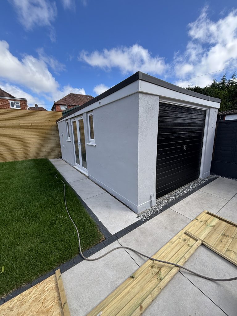 Freshly painted white rendered garage exterior in Southampton with a black roller door, completed by Solent Property Finishing.