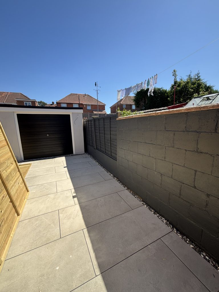 Garden boundary wall and concrete fence panels freshly painted in dark grey masonry paint in Southampton, creating a modern exterior finish.